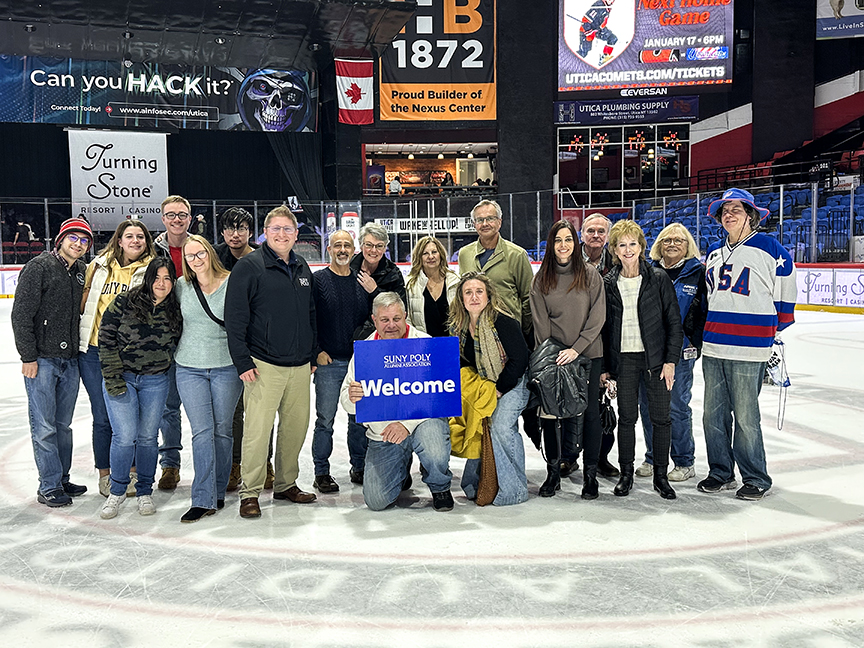 Group of alumni and staff at center ice at the Utica Comets Hockey game.