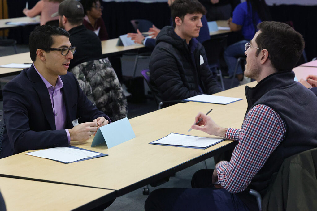 Two professionals speaking and taking notes during a networking session.