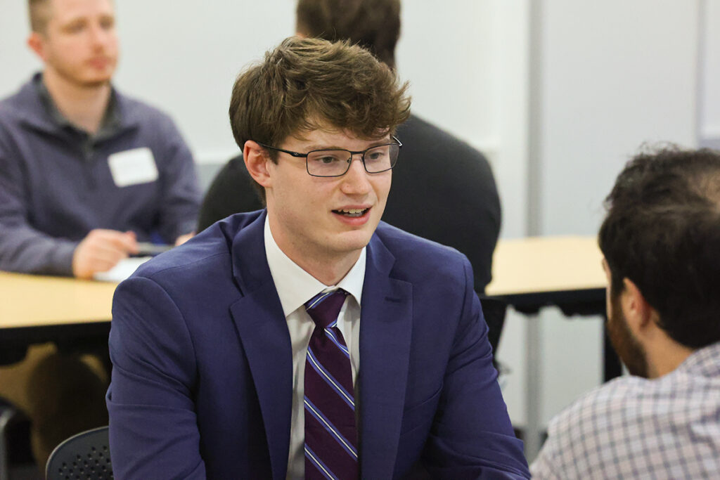 Student in a suit participating in a one-on-one conversation at a networking event.