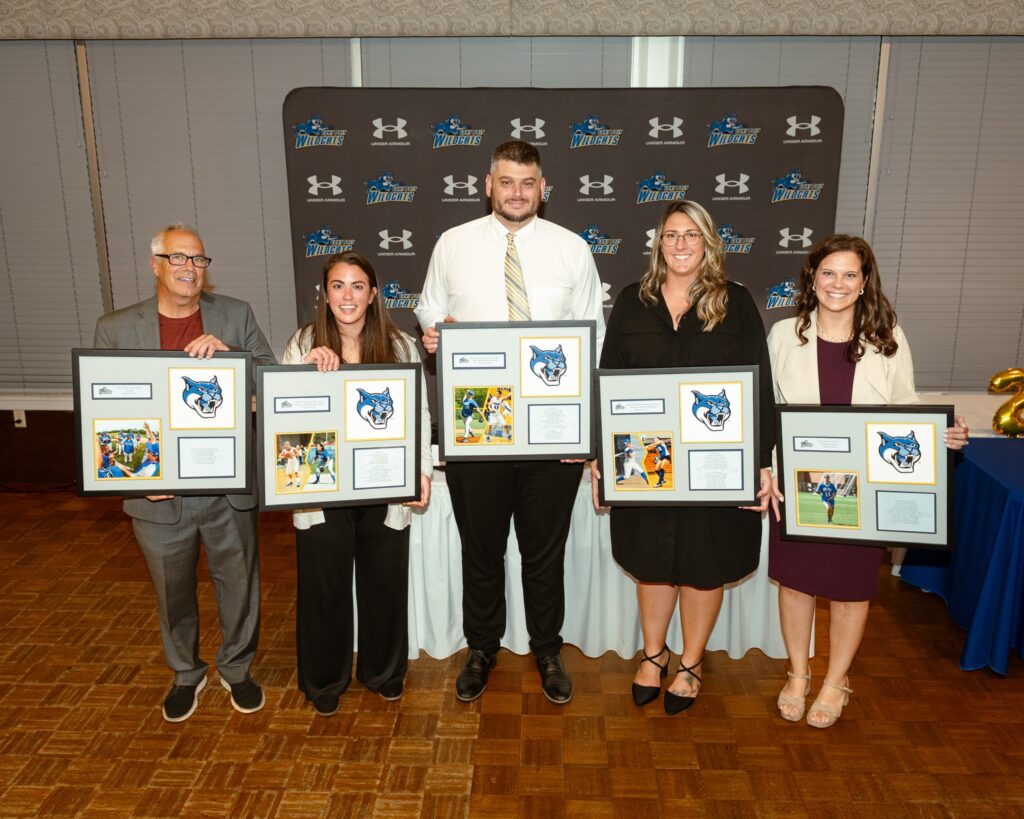 Group of Athletic staff holding framed awards.