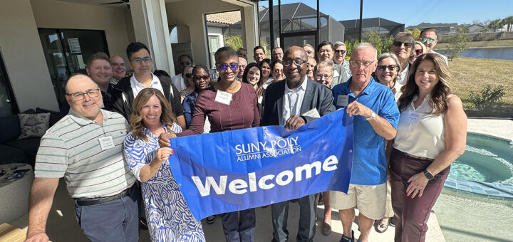 Alumni and staff gathered and holding a Welcome banner in Florida.